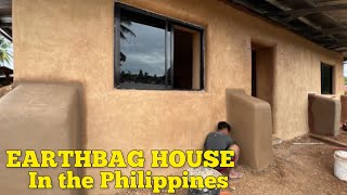 🛖PART27 earthbag house WINDOW FRAMES BEING INSTALLED ampFINAL EARTHERN PLASTER ON THE OUTSIDE WALLS [upl. by Aynod873]